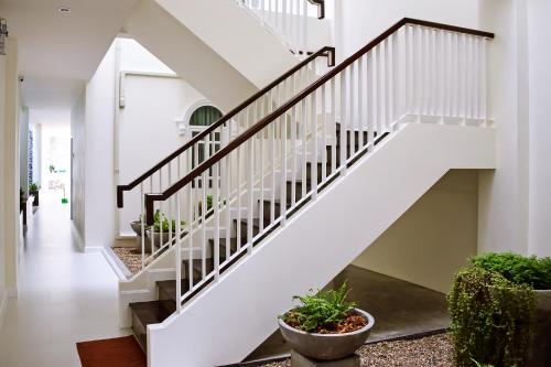 a white staircase in a house with potted plants at Shunli Hotel - SHA Extra Plus in Phuket Town
