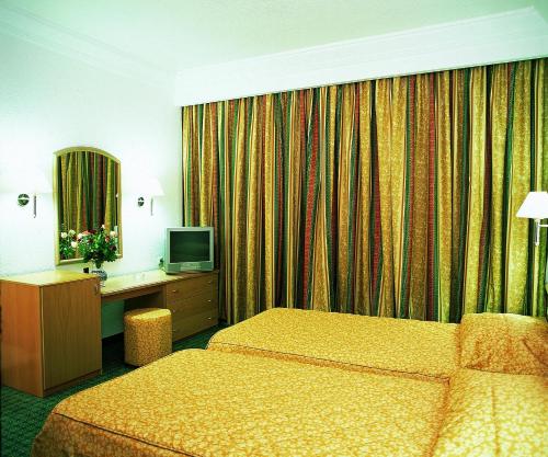 a hotel room with two beds and a television at El Mouradi Skanes in Monastir
