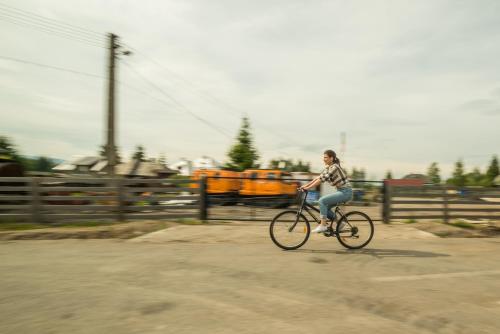 a woman riding a bike down a street at Pensiunea Vis Alpin Belis in Beliş