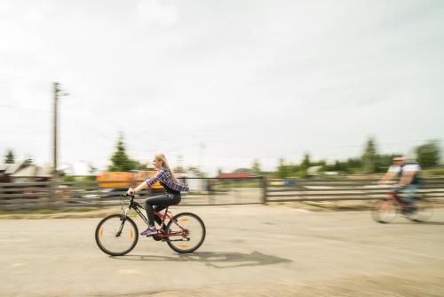 a woman riding a bike down a street at Pensiunea Vis Alpin Belis in Beliş