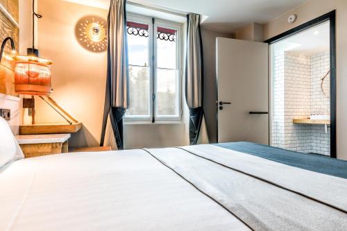 a bedroom with a large white bed and a window at Hotel Restaurant Au Boeuf Couronné in Paris