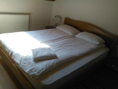 Una cama con sábanas blancas y almohadas. en Pensiunea Casa Szabi, en Luna de Sus