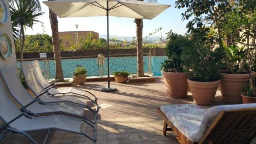 a patio with a chair and an umbrella and a pool at Villa Mosè Apartment, parking, terrace in Villaggio Mosè