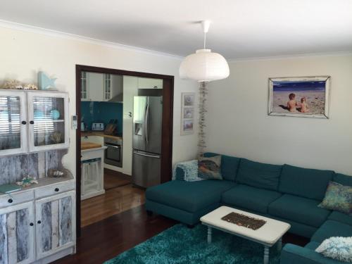 a living room with a blue couch and a kitchen at Aqua Shack Jurien Bay in Jurien Bay