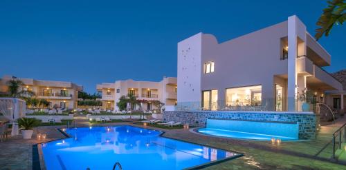 a villa with a swimming pool at night at Kristalli Hotel Apartments in Malia