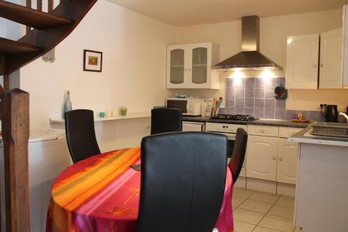 eine Küche mit einem Tisch mit Stühlen und einem Herd in der Unterkunft Maison Sous les Platanes in Saint-Pantaléon-les-Vignes