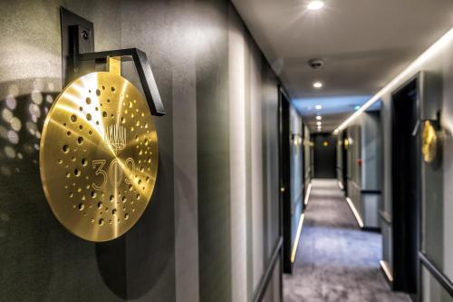 a gold clock on the wall of a hallway at Hotel Restaurant Au Boeuf Couronné in Paris