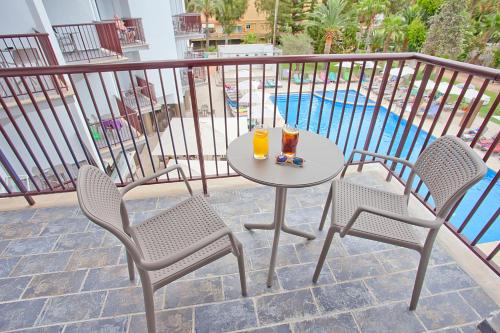 een tafel met 2 stoelen en 2 drankjes op een balkon bij FERGUS Bermudas in Palmanova