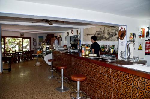 Un uomo in piedi in un bar in un ristorante di Hostal Alocs a Playa d'Es Figueral