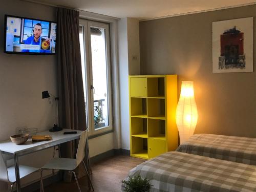 1 dormitorio con cama, escritorio y TV en la pared en Hôtel de la Mare en París