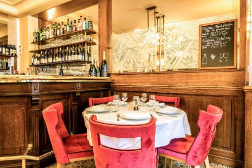 a table in a restaurant with red chairs and a bar at Hotel Restaurant Au Boeuf Couronné in Paris