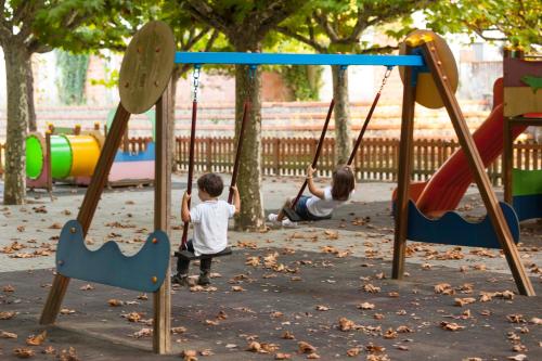 two young boys playing on a swing set at a playground at Hotel Termas da Curia in Curia
