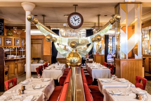 a restaurant with white tables and a clock on the wall at Hotel Restaurant Au Boeuf Couronné in Paris