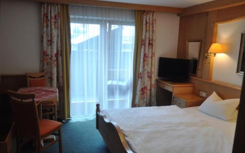 a hotel room with a bed and a television at Aktiv-Hotel Traube am Mieminger Sonnenplateau in Wildermieming