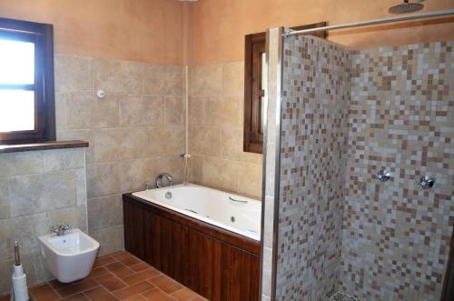 een badkamer met een bad, een wastafel en een douche bij Ca Na Marina in Cala Llombards