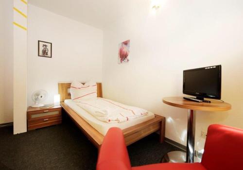 a small bedroom with a bed and a tv at Hotel Goldener Hahn in Duisburg