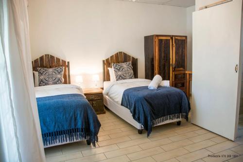 1 dormitorio con 2 camas con sábanas azules y blancas en Die Kasteel, en Hartswater