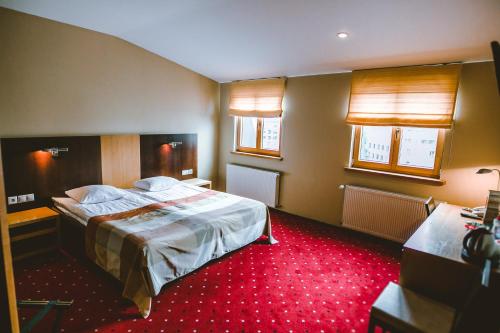 a hotel room with a bed and two windows at Hanza Hotel in Rīga