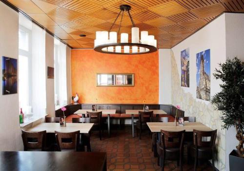 a dining room with tables and chairs and a chandelier at Hotel Goldener Hahn in Duisburg