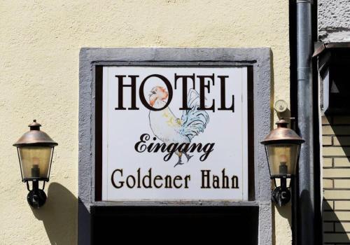 a sign on the side of a building with two lights at Hotel Goldener Hahn in Duisburg