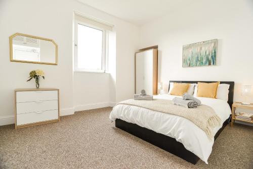 a bedroom with a bed and a dresser and a mirror at Modern Central Apartment in Aberdeen