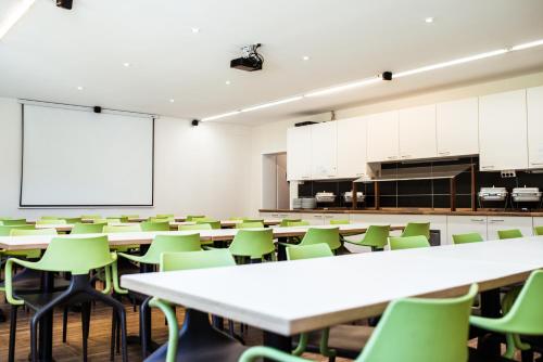 an empty classroom with tables and green chairs at FT Hotel & Restaurant in Freiburg im Breisgau