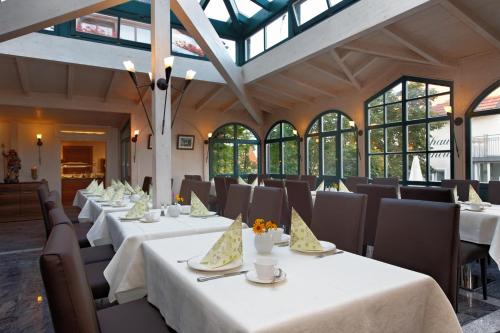 un comedor con mesas y sillas blancas y ventanas en Landhotel Schneider, en Riedenburg