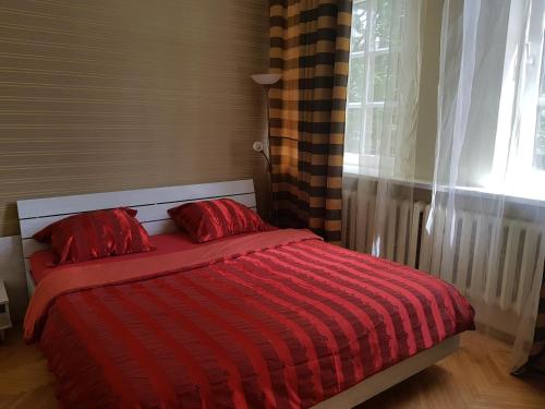 a red bed with two red pillows in a bedroom at Vilhelm's Apartment in Klaipėda