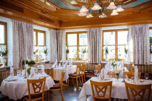 a restaurant with white tables and chairs and windows at Landhotel Schneider in Riedenburg