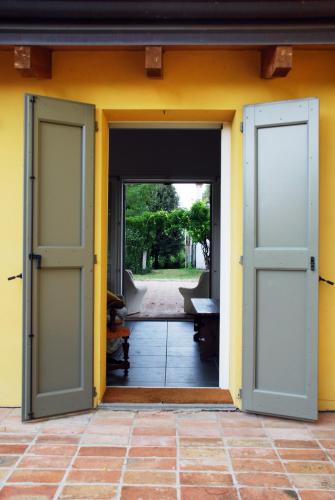 an open door of a house with a yellow wall at Casale13 in Faenza