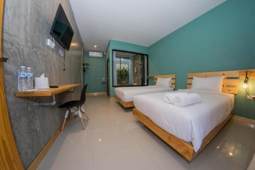 a hotel room with two beds and a desk and a television at Rest Time Hotel in Nong Khai