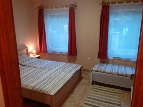 een slaapkamer met 2 bedden en rode gordijnen bij Éva vendégház Guesthouse in Hajdúszoboszló