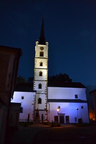 a white building with a clock tower at night at Pension U Kostela in Frymburk