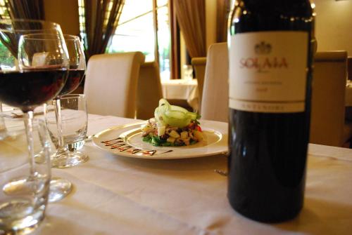 a bottle of wine sitting on a table with a plate of food at Albergo Giardino in Cernobbio