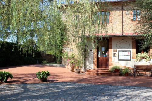 a brick building with a tree over a brick driveway at Agriturismo Antico Borgo Poggitazzi in Loro Ciuffenna