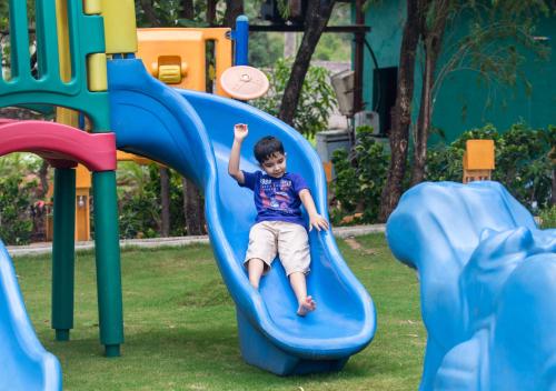 a boy sliding down a slide at a playground at Residency Lake Resort & Spa in Mulshi