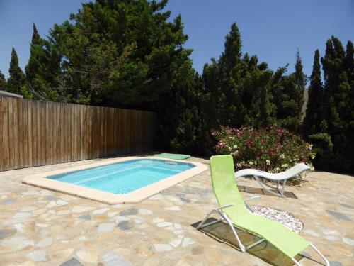 a swimming pool with two lawn chairs next to a fence at Cortijillo Violeta in Agua Amarga