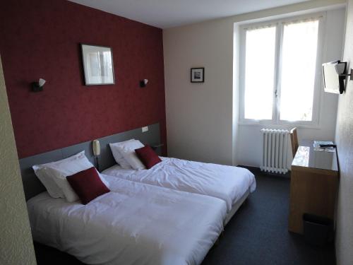 a hotel room with two beds and a window at Hôtel Ambroise in Uzerche