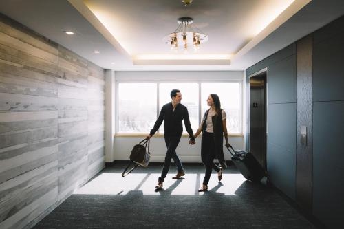 a man and woman walking through a hallway with their luggage at Inn at the Forks in Winnipeg