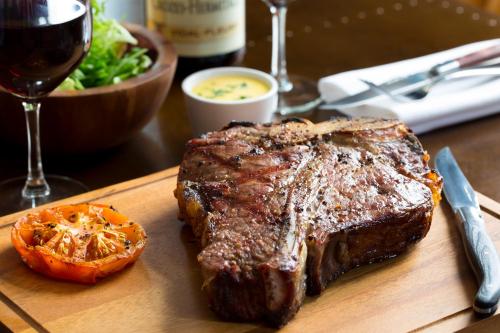 a steak on a cutting board with a salad and a glass of wine at The Porterhouse grill & rooms in Oxford