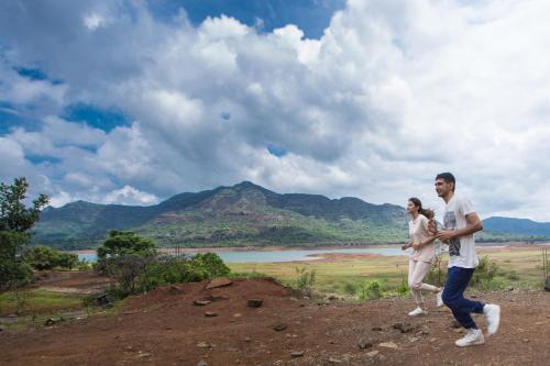 a man and a woman walking on top of a hill at Residency Lake Resort & Spa in Mulshi