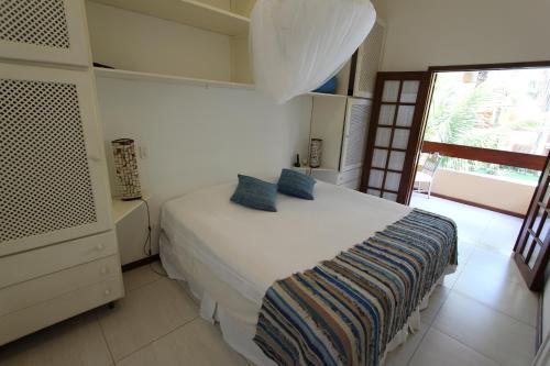 a bedroom with a white bed with blue pillows at Casa 31 Paraty in Paraty