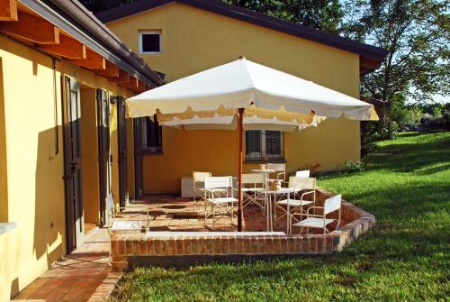 a patio with a table and chairs under an umbrella at Casale13 in Faenza