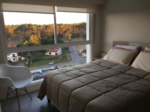 1 dormitorio con cama y ventana grande en Green Life - Club Vacacional y SPA, en Punta del Este