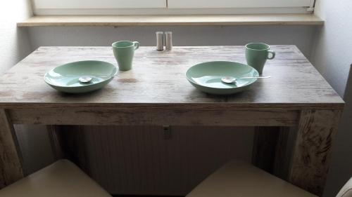una mesa de madera con dos tazones y dos tazas. en Schwalbennest, en Fürth
