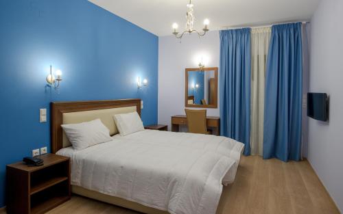 una camera con letto bianco e pareti blu di Hotel Anna a Ioannina