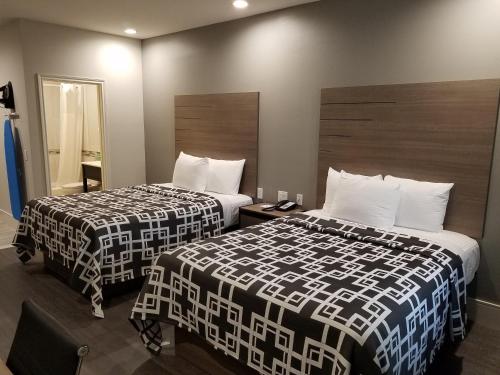 a hotel room with two beds and a mirror at Palace Inn Blue Tomball Parkway in Houston