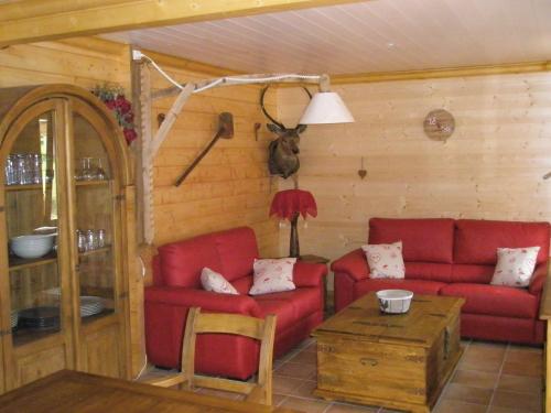 a living room with red couches and a table at Chalet Mauselaine in Xonrupt-Longemer