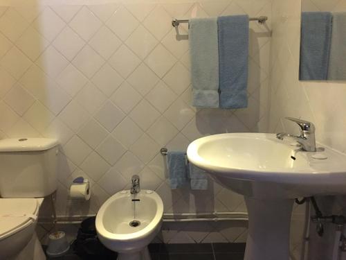 a white bathroom with a sink and a toilet at Casa do Brigadeiro in Lajeosa