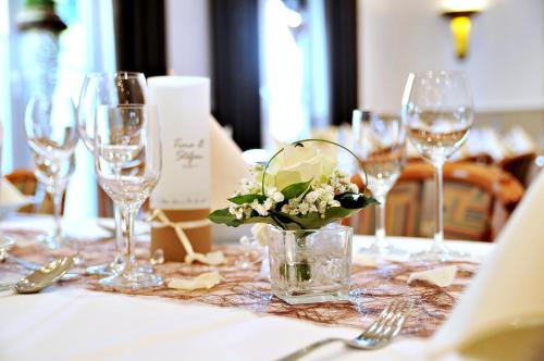a table with wine glasses and a vase with flowers at Hotel Restaurant Bürgerklause Tapken in Garrel